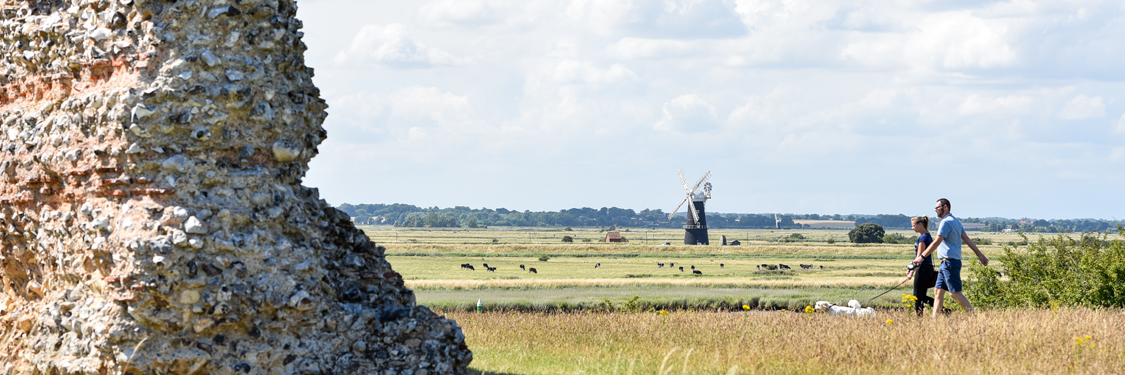 two people walking their dog at burgh castle
