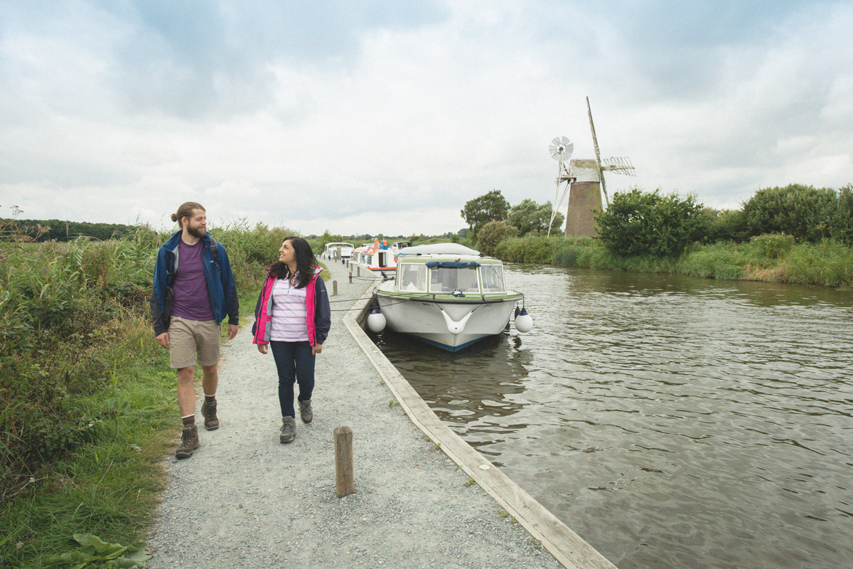 two people walking at how hill with turf fen mill in the background