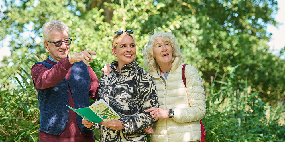 A family on a walk holding a walking leaflet