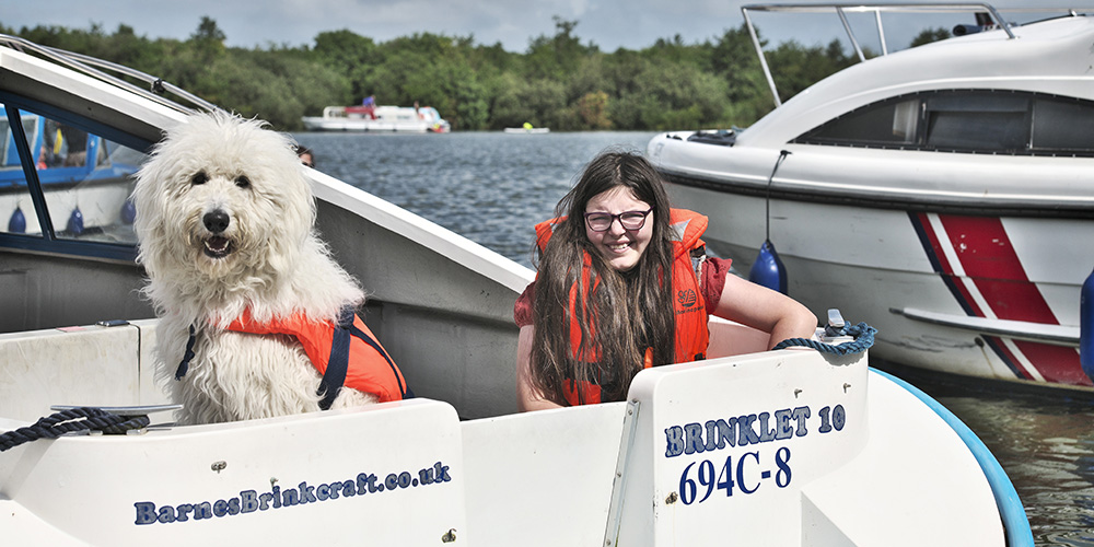 A young girl and a dog aboard a motor cruiser