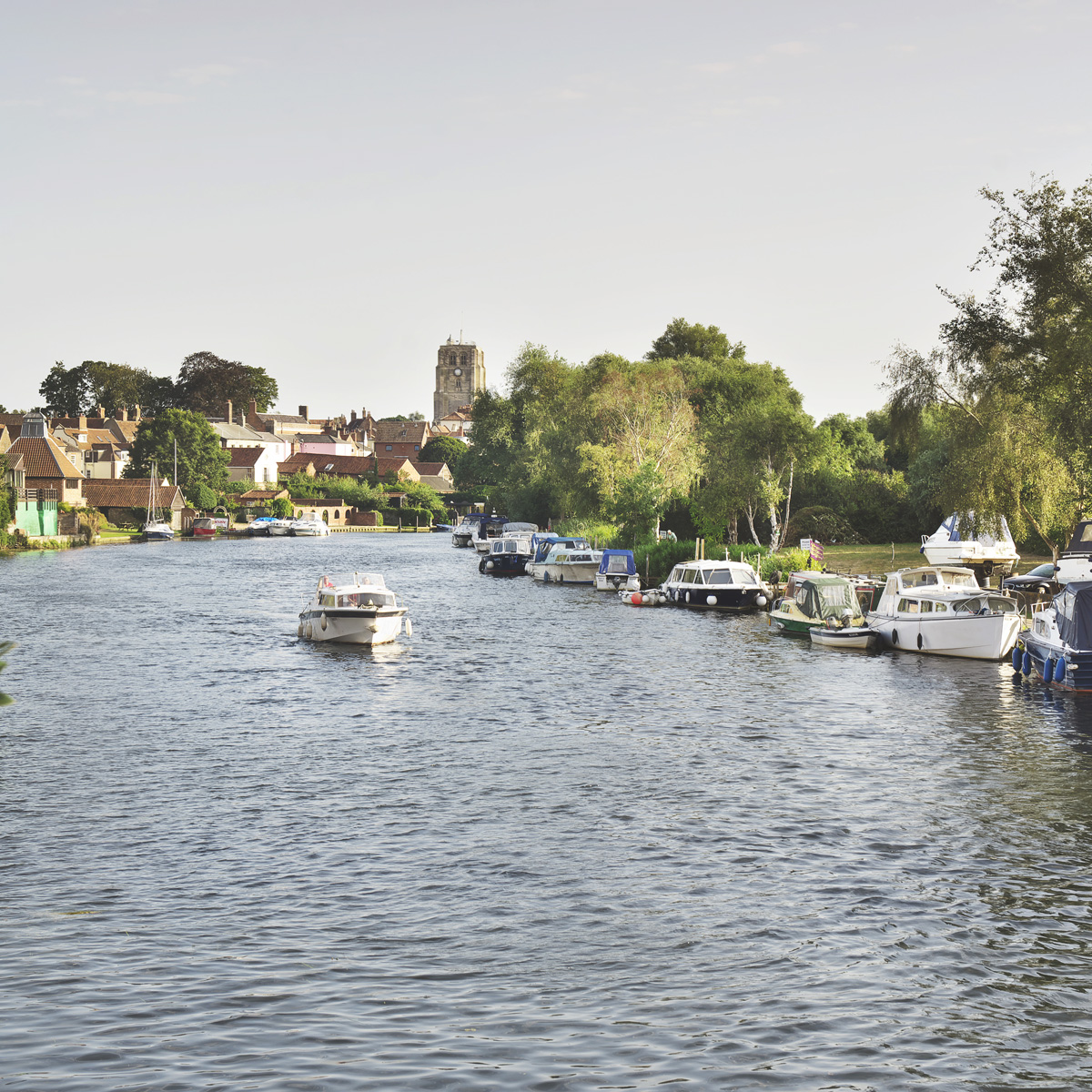 Boat travelling down the river waveney, with historic buildings visible in the background