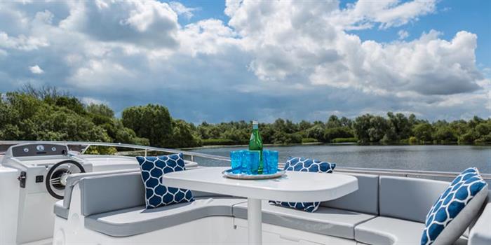 Broom Boats holiday cruiser passing reed-lined banks on the Broads