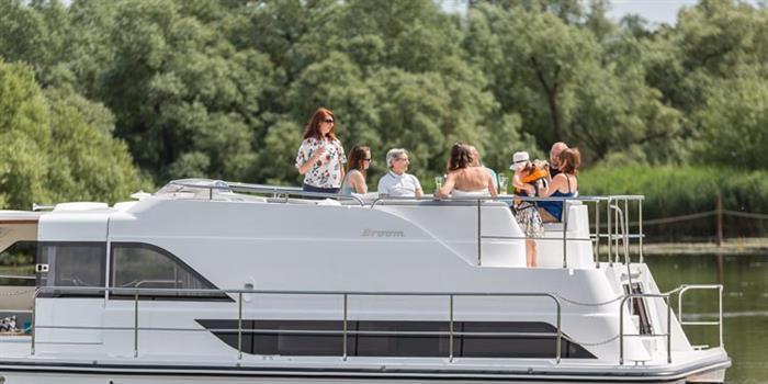 Friends relaxing on deck of a Broom Boats holiday cruiser on the Norfolk Broads