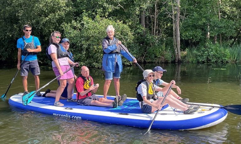 A group of people enjoying the giant paddleboard from Nancy Oldfield Trust