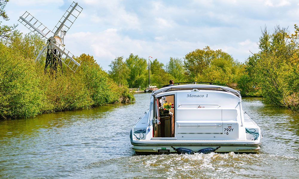 Rear view of the Monaco 1 cruiser passing a traditional windmill on the Norfolk Broads.
