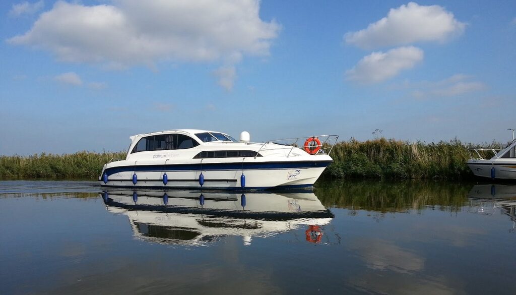A holiday hire boat with a full reflection of it in still water