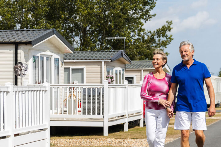 A middle aged couple stroll through lodges, hand in hand