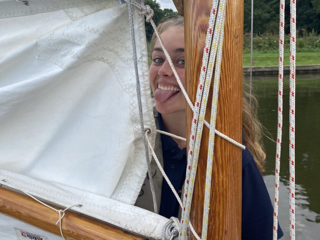 Girl peering through a sail and playfully sticking out her tongue