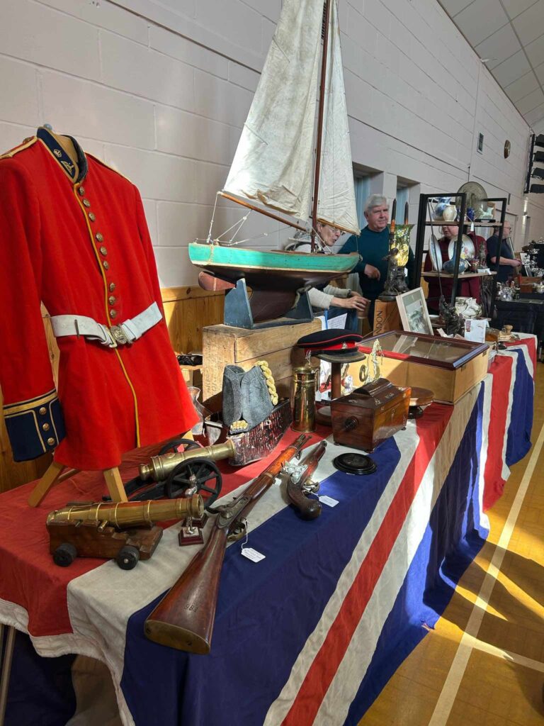 Stall at antique fair in Loddon, red military jacket and model yacht on display